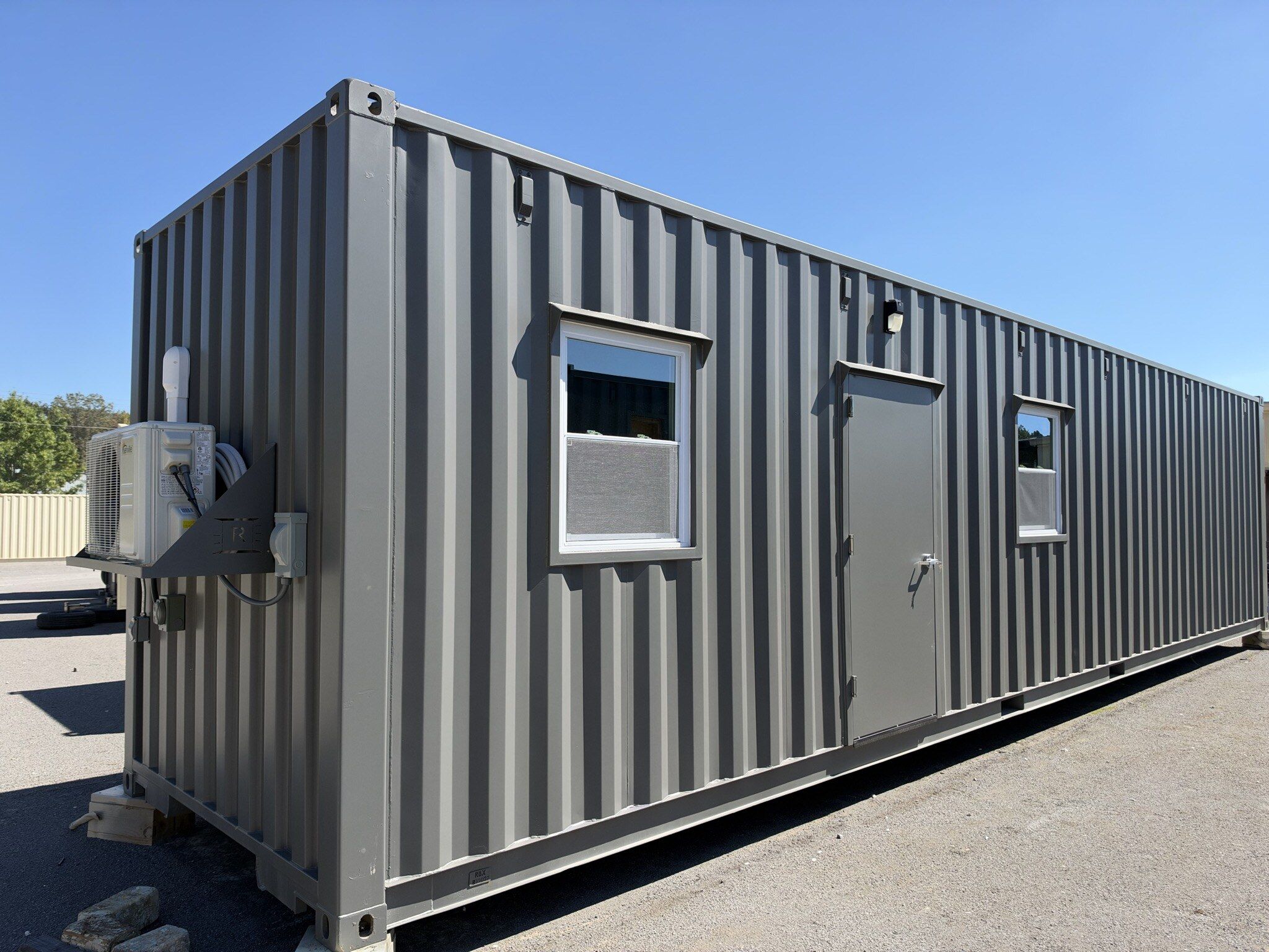 A Rebox 40' ground level office with two windows, a steel entry door, and a mini split heat pump.