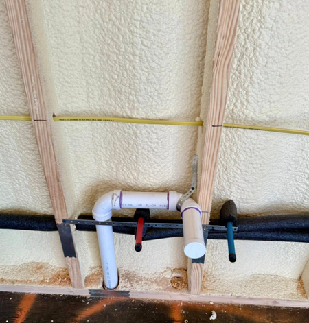 A view of a finished wall in a Rebox Solutions container, with spray foam insulation and plumbing and electrical roughed in.